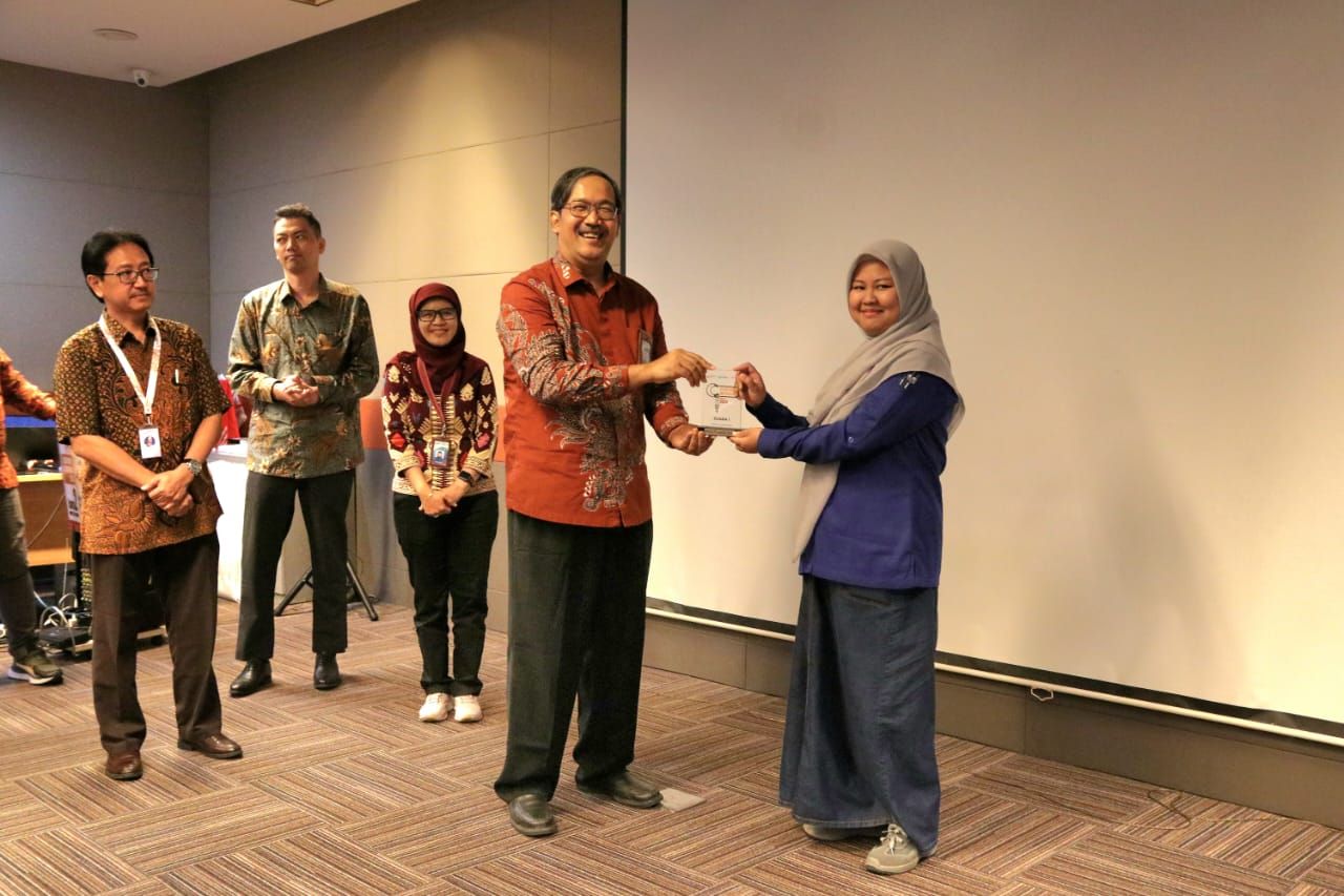 Deputi SNSU BSN - Y Kristianto Widiwardono menyerahkan hadiah kepada Rina Puspita Sari - Laboran dari Politeknik ASTRA sebagai Juara I Olimpiade Metrologi untuk Kategori Industri