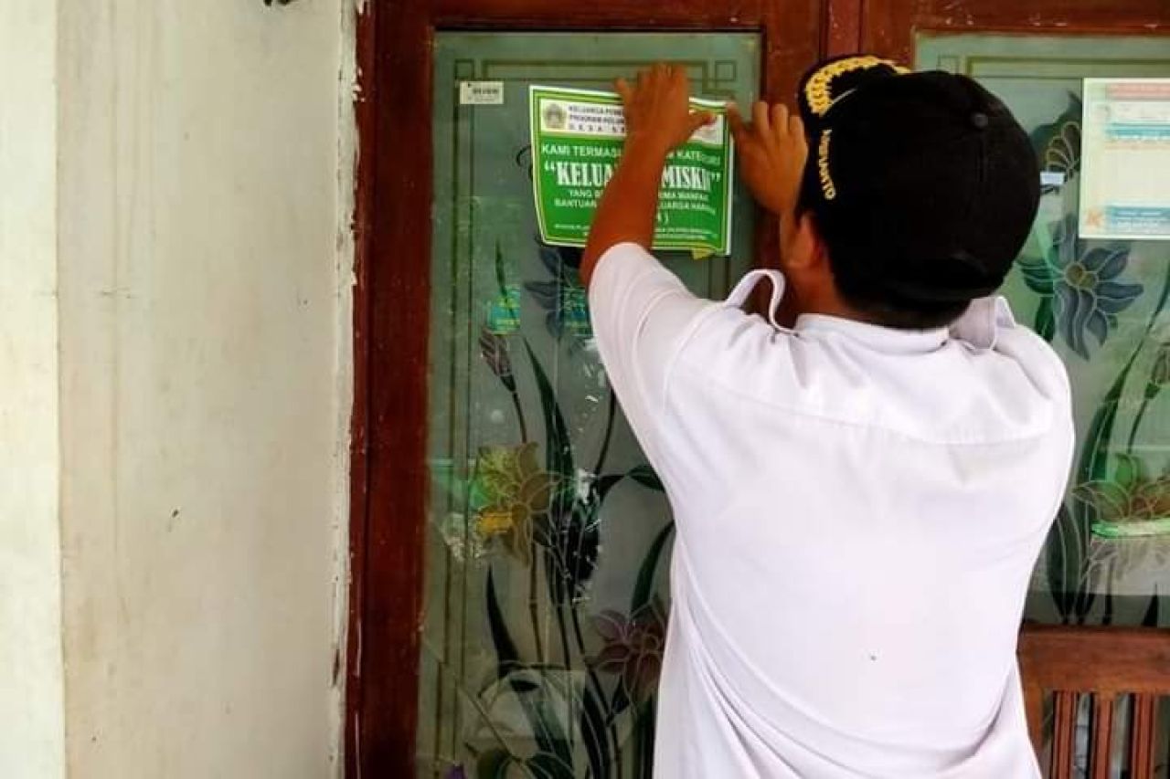 Petugas menempelkan stiker "keluarga miskin" di rumah warga