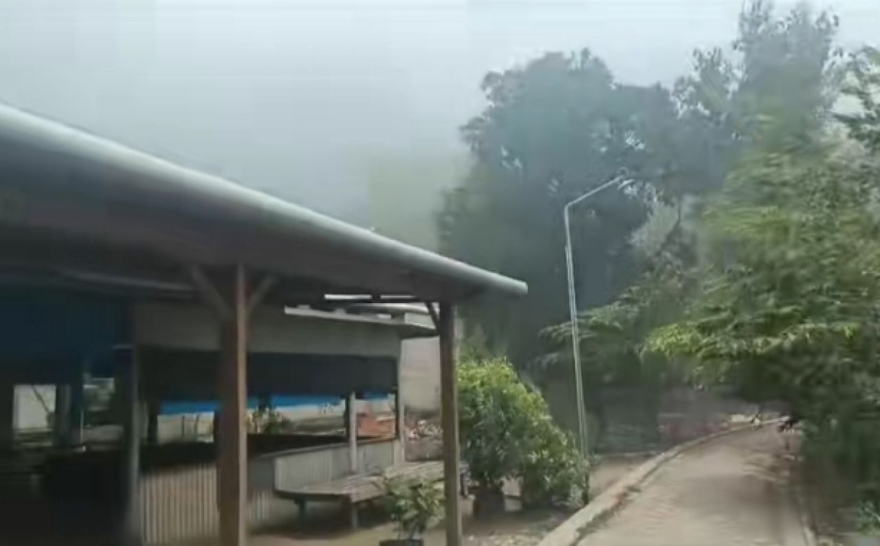 Seorang warga di tengah kepulan asap dari TPST Desa Trosobo