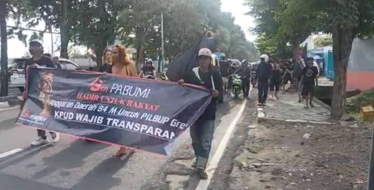 Massa membentangkan spanduk menuju gedung DPRD Gresik