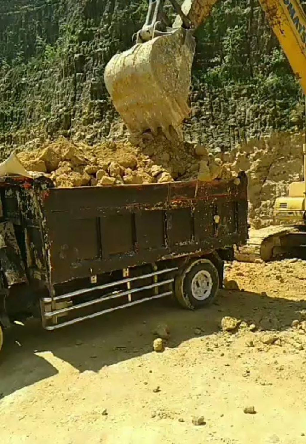 Excavator menaikkan material tambang ke atas truk