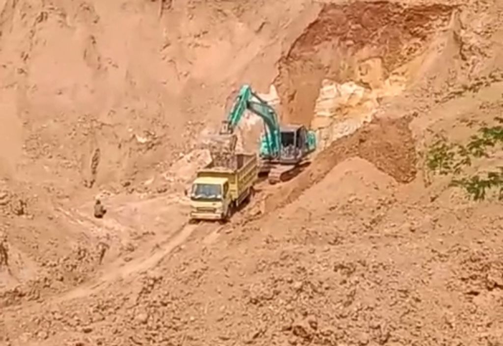Tampak ekscavator sedang mengisi material tambang ke atas bak dump truk